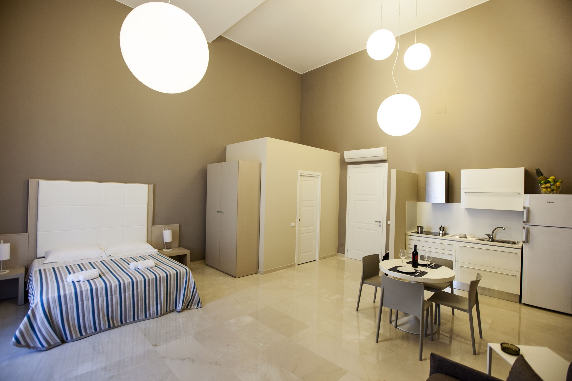 Una habitación de hotel moderna con una cama grande, un comedor y una kitchenette.