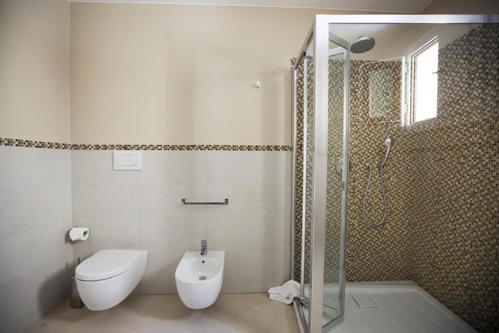 A bathroom with a toilet, bidet, and glass-enclosed shower area.