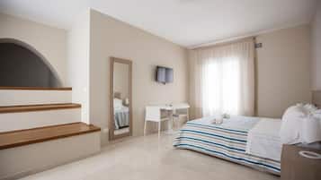 Una habitación de hotel con cama, escritorio, silla, televisor y escalera.