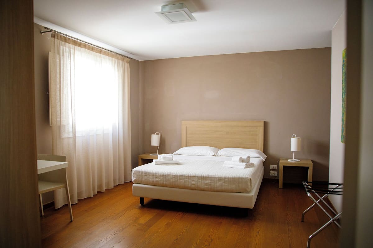 Un dormitorio ordenado con cama, mesitas de noche y un escritorio.