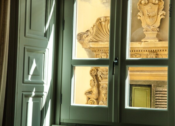 Una habitación con un ventanal grande, un relieve de piedra decorativo y una puerta verde.