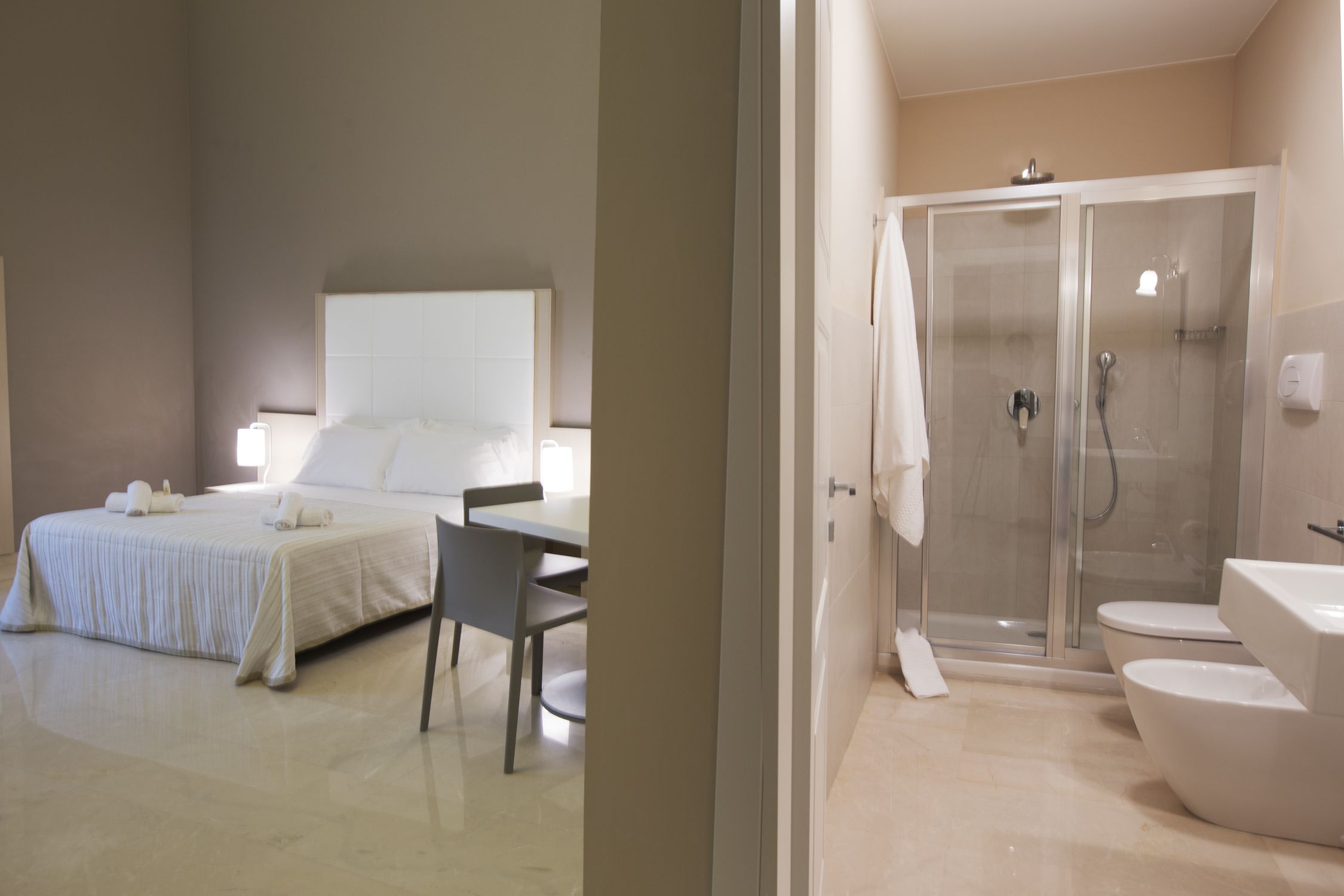 Una habitación de hotel con cama, una silla, ducha y baño.