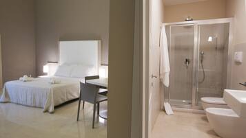 Una habitación de hotel con cama, una silla, ducha y baño.
