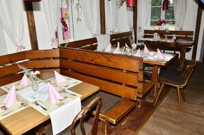 A restaurant with wooden furniture, white tablecloths, and pink napkins.