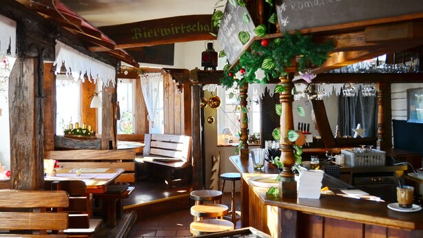 Un interior rústico con muebles de madera, una zona de bar y un menú en la pizarra.