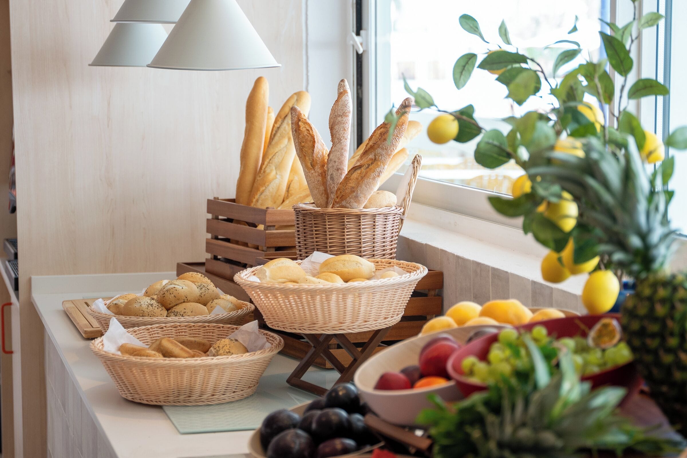 Una mesa de buffet con panes en cestas, frutas y un bol de uvas.