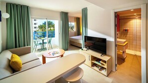 Un salon moderne comprenant un canapé, un téléviseur et un coin repas, un balcon avec vue et une salle de bain avec douche et lavabo.