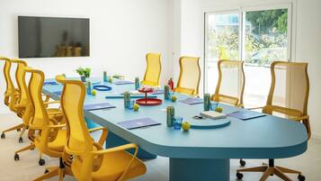 A conference room with a blue table, yellow chairs, and a large window.