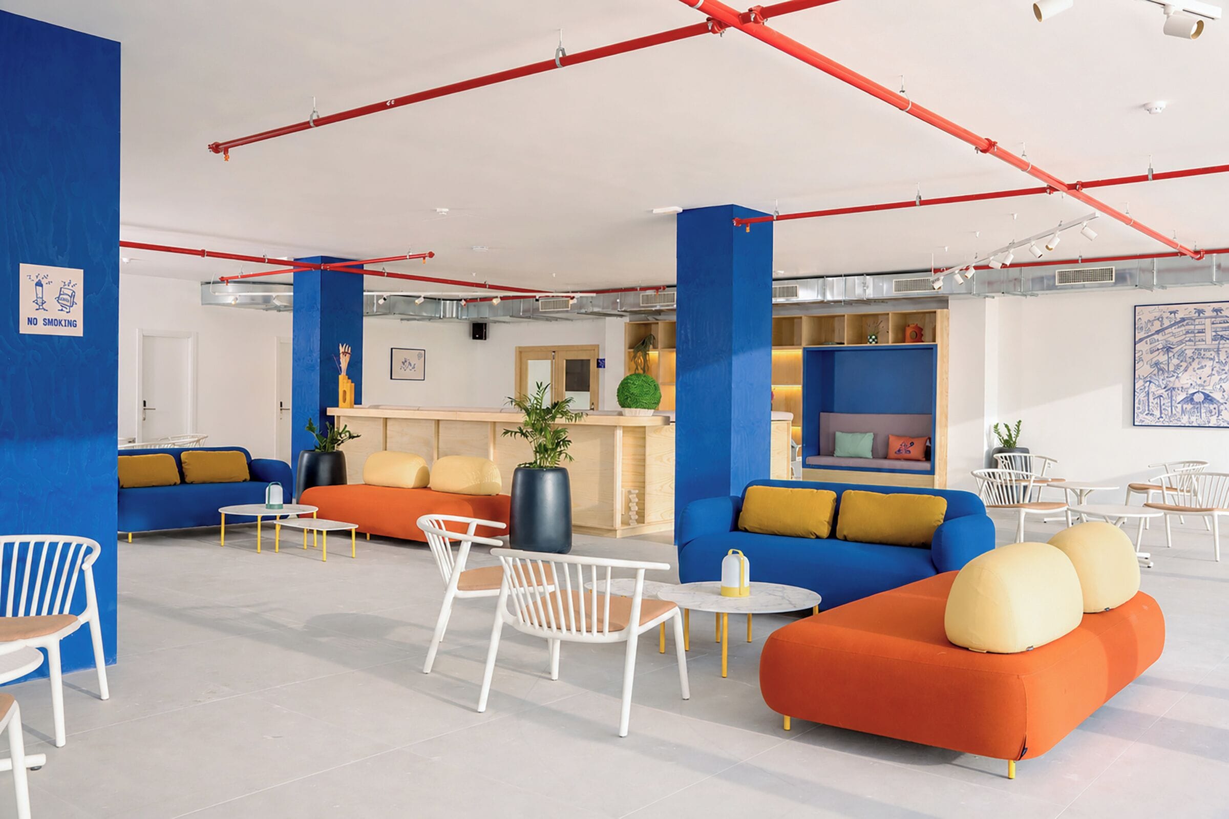 A modern lounge area with seating arrangements, a reception desk, and a blue accent wall.