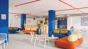 A modern lounge area with seating arrangements, a reception desk, and a blue accent wall.