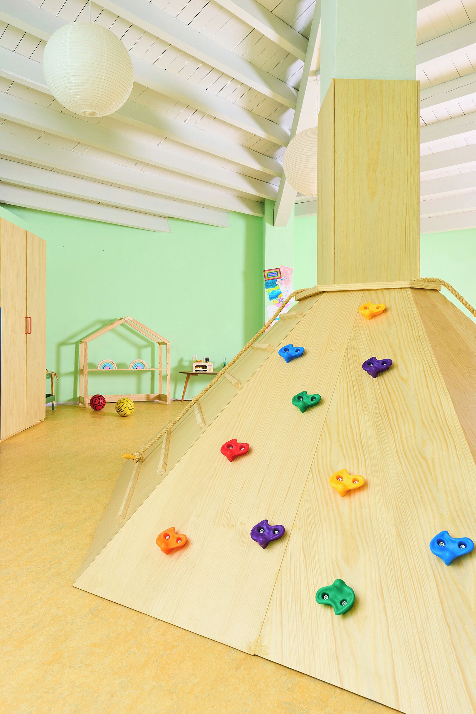 A children's play area with a wooden slide and climbing holds.