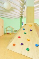Zona de juegos infantiles con un tobogán de madera y puntos de agarre para escalar.