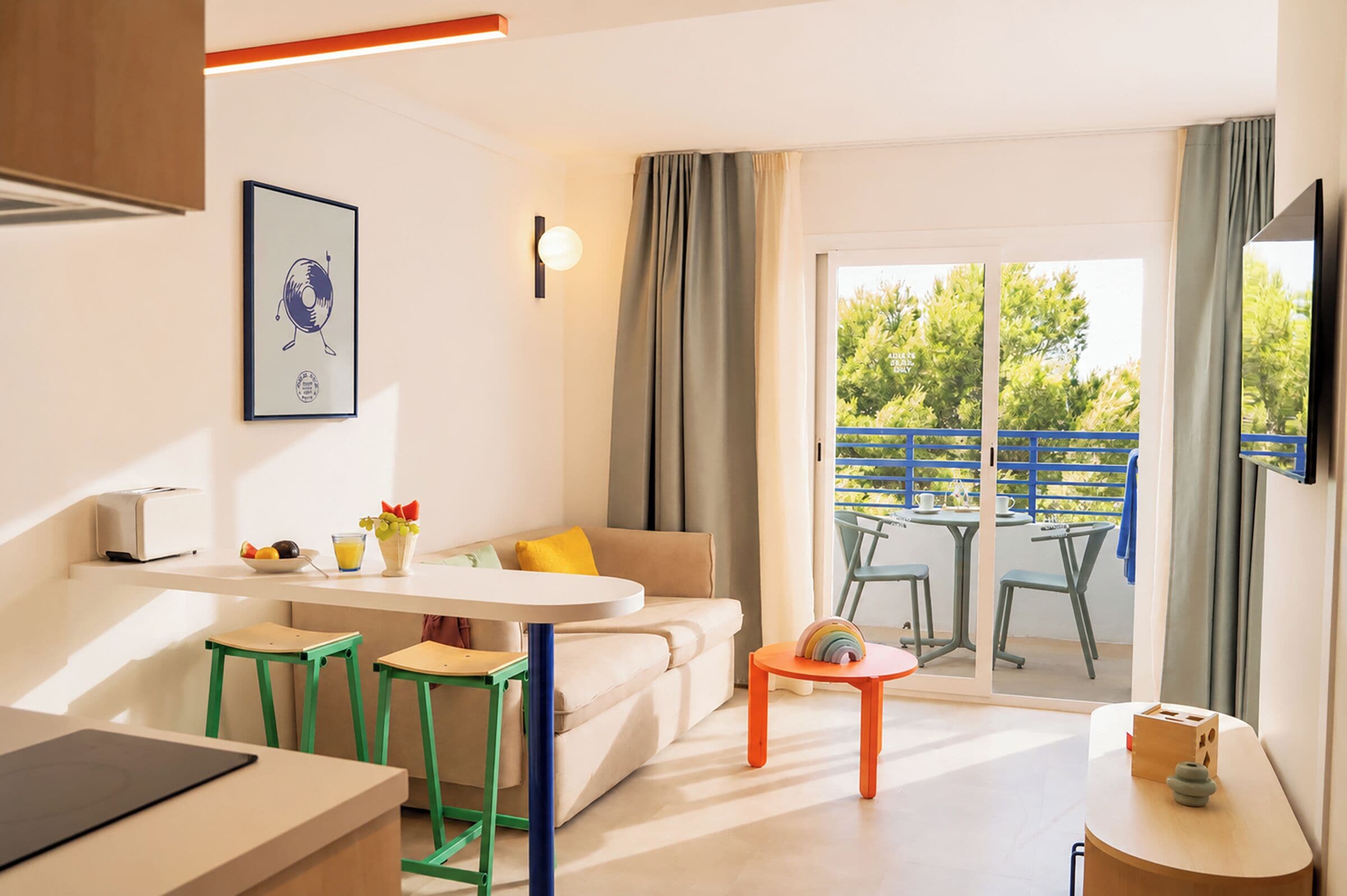 A modern kitchen with a dining area, a sofa, and a table with chairs.
