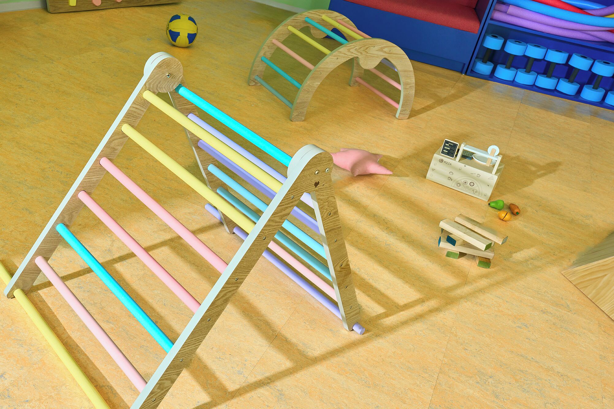 Une structure de jeu en bois avec des barres colorées, une petite maison de poupée et une boîte à jouets sur le thème de la pizza.