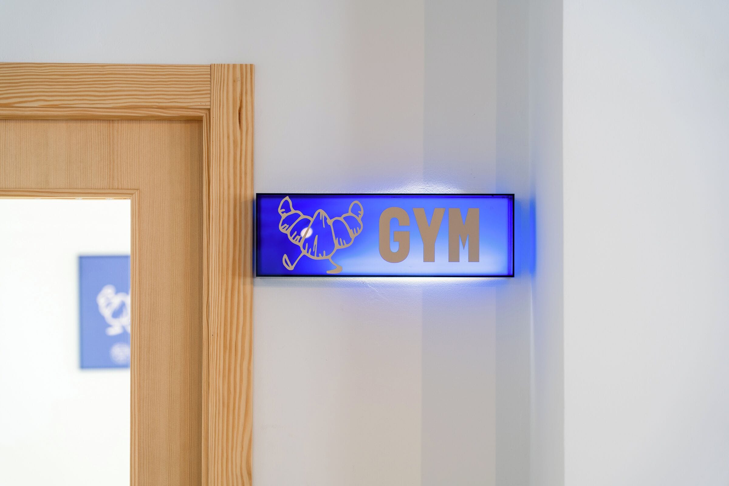 A blue illuminated sign with the word 'GYM' and a silhouette of a person exercising.
