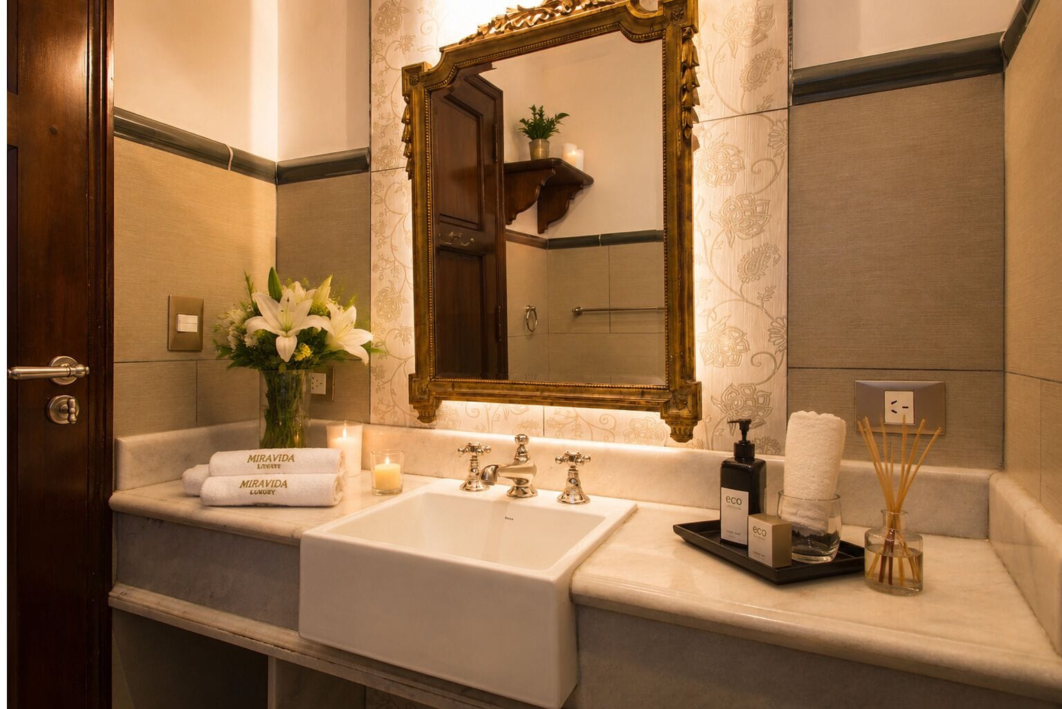 Un baño con un espejo grande, un lavamanos y un perchero para toallas.