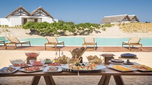 Un buffet situé au bord de la plage, proposant divers plats, avec vue sur la piscine.