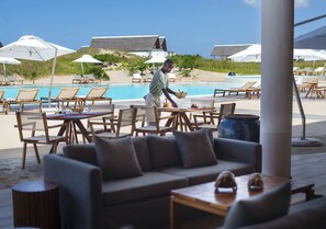 A poolside area with lounge chairs, umbrellas, and a dining setup. - Mequfi Beach Resort (Mecufi)