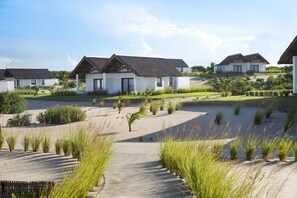 A resort with multiple white buildings, a paved walkway, and landscaped areas with grass and plants. - Mequfi Beach Resort (Mecufi)
