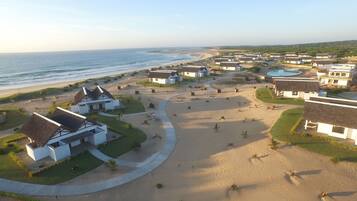 A coastal resort with multiple bungalow-style buildings, a sandy beach, and a view of the ocean.