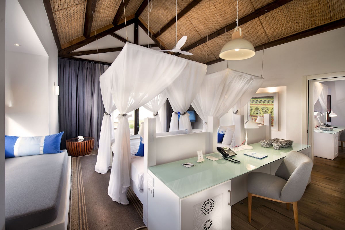 Una habitación de hotel moderna con una cama, un escritorio, una silla, una mesita de noche, un teléfono y una ventana con cortinas.