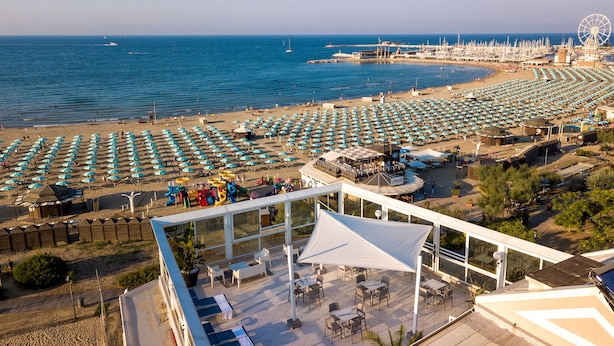 A beach with rows of umbrellas and a Ferris wheel in the background. - Hotel Baia Imperiale & Spa (Rimini)