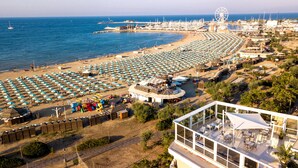 A beachside hotel with a large outdoor seating area, a children's play area, and a view of the sea and marina. - Hotel Baia Imperiale & Spa (Rimini)