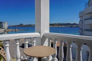 A balcony with a table and chairs, overlooking a coastal area with buildings and a clear sky. - ENDLSS BEACH & DISCO HOTEL IBIZA ADULTS ONLY (Sant Josep de sa Talaia)