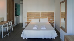Une chambre d’hôtel comprenant un lit, un bureau, une chaise, une table de chevet et un miroir.