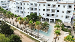 Un hôtel à plusieurs étages doté de balcons, d’une piscine et de palmiers.
