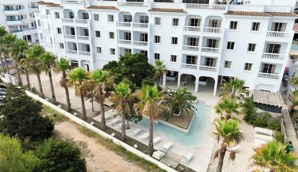A multi-story hotel with balconies, a swimming pool, and palm trees. - ENDLSS BEACH & DISCO HOTEL IBIZA ADULTS ONLY (Sant Josep de sa Talaia)