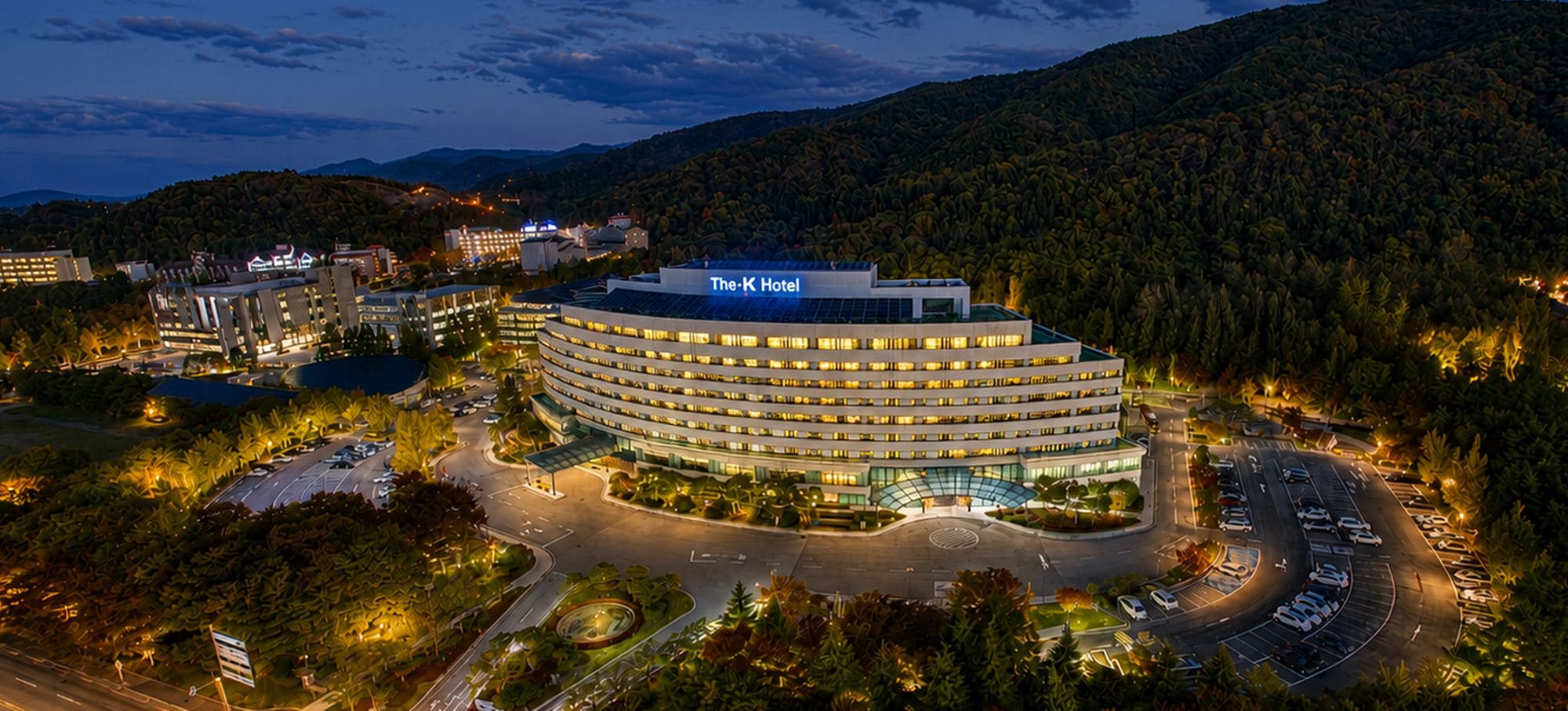 A modern hotel with a circular design, multiple floors, and a parking area.