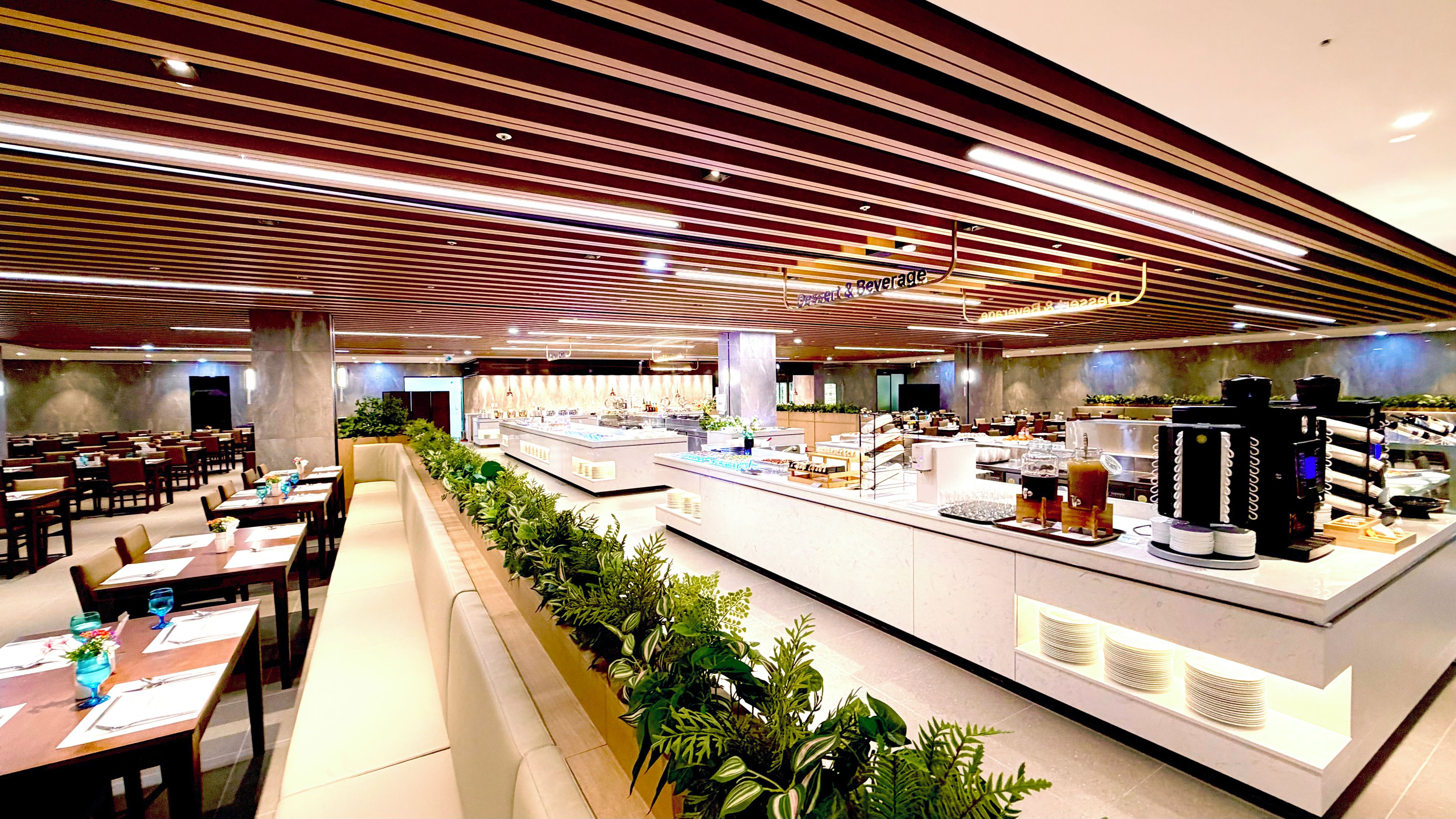 Un restaurante moderno con una barra larga, varias zonas de estar y una cafetería.