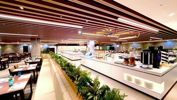 Un restaurante moderno con una barra larga, varias zonas de estar y una cafetería.