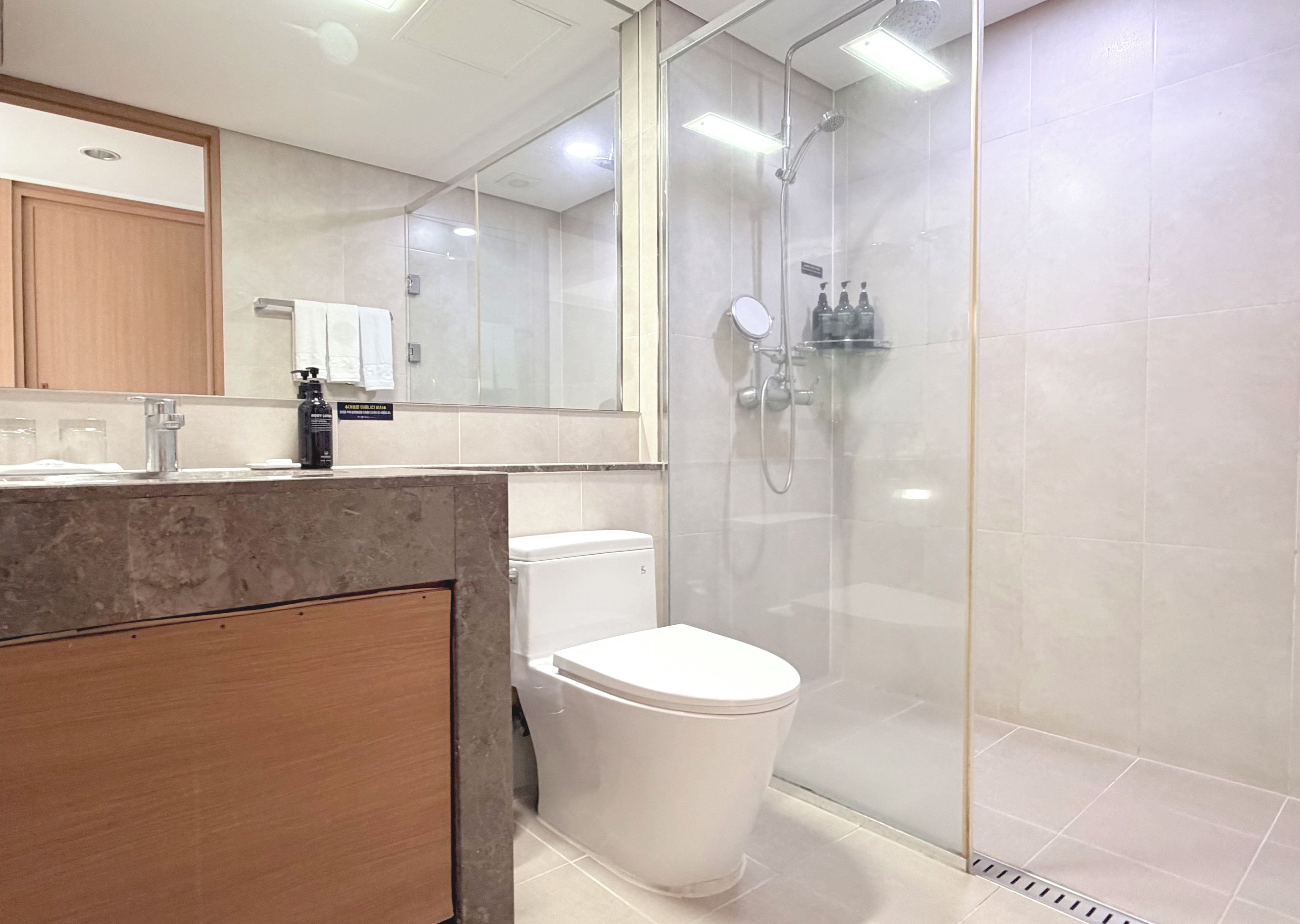 A modern bathroom with a glass-enclosed shower, a white toilet, and a marble countertop.