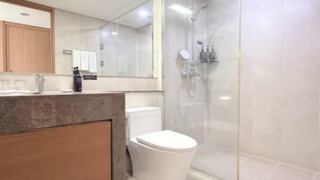 A modern bathroom with a glass-enclosed shower, a white toilet, and a marble countertop.