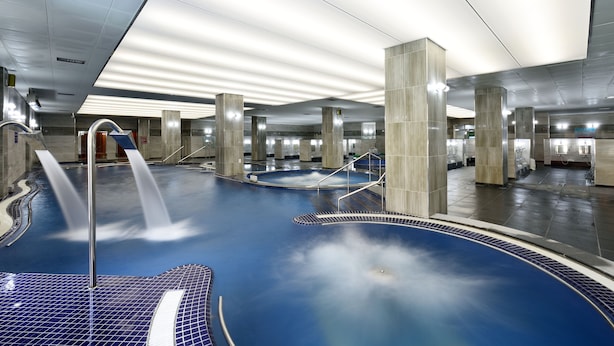Una piscina interior moderna con múltiples carriles, una fuente central y un diseño espacioso.