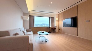Una habitación de hotel moderna con un ventanal grande, un televisor de pantalla plana, un sofá y una mesita.