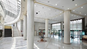 A spacious lobby with high ceilings, large columns, and a central staircase. - The K Hotel Gyeongju (Gyeongju)
