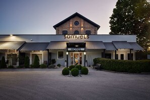 A hotel named Samuels with a modern design, featuring a prominent entrance, a clock, and a well-maintained garden area. - Samuel's Boutique Hotel (Ashfield-Colborne-Wawanosh)