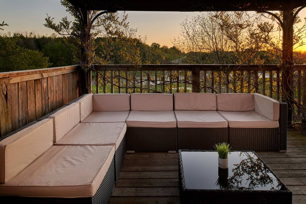 A wooden deck with a sectional sofa and a glass-top coffee table.