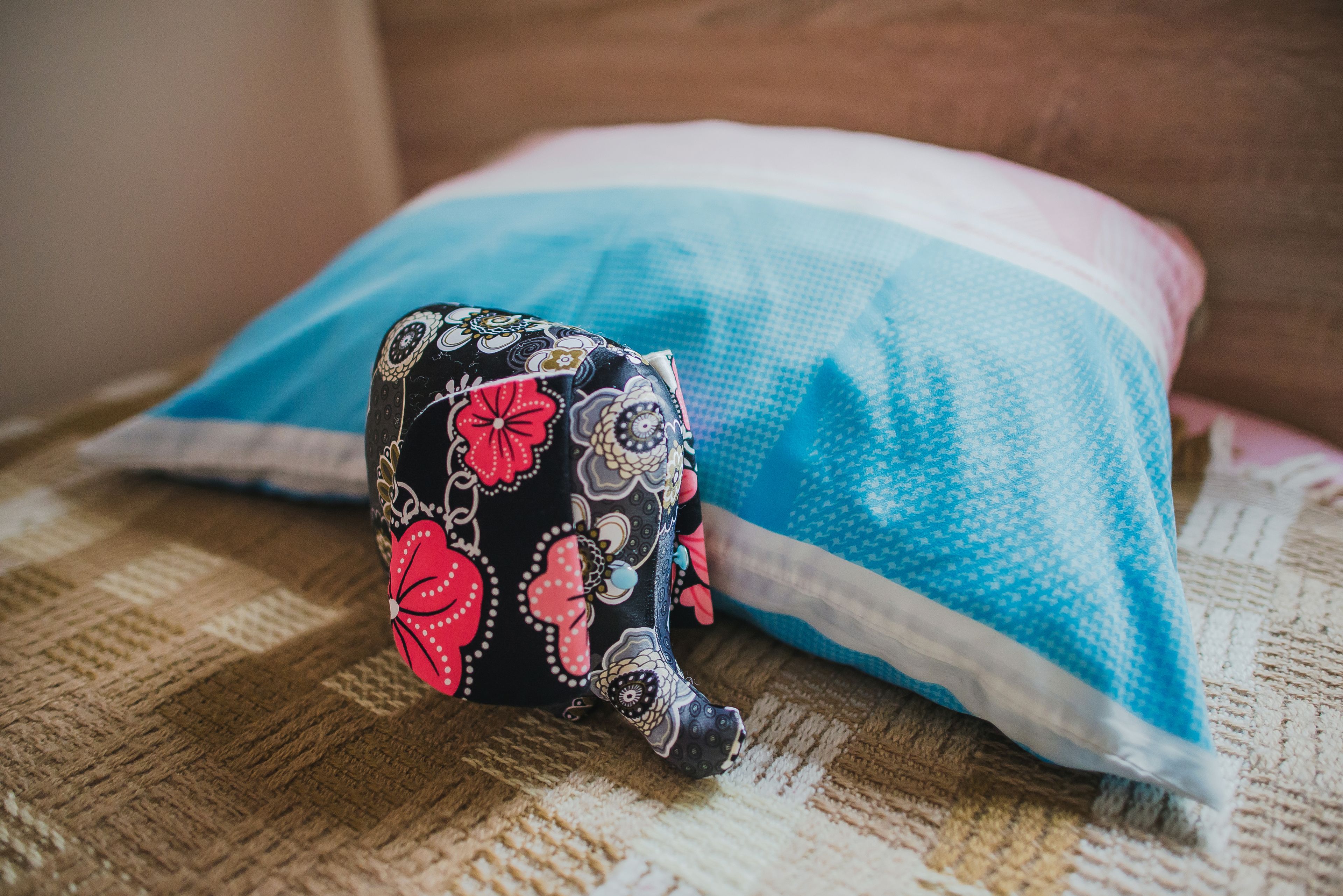 A pillow with a floral pattern and a blue and white striped pillow behind it.