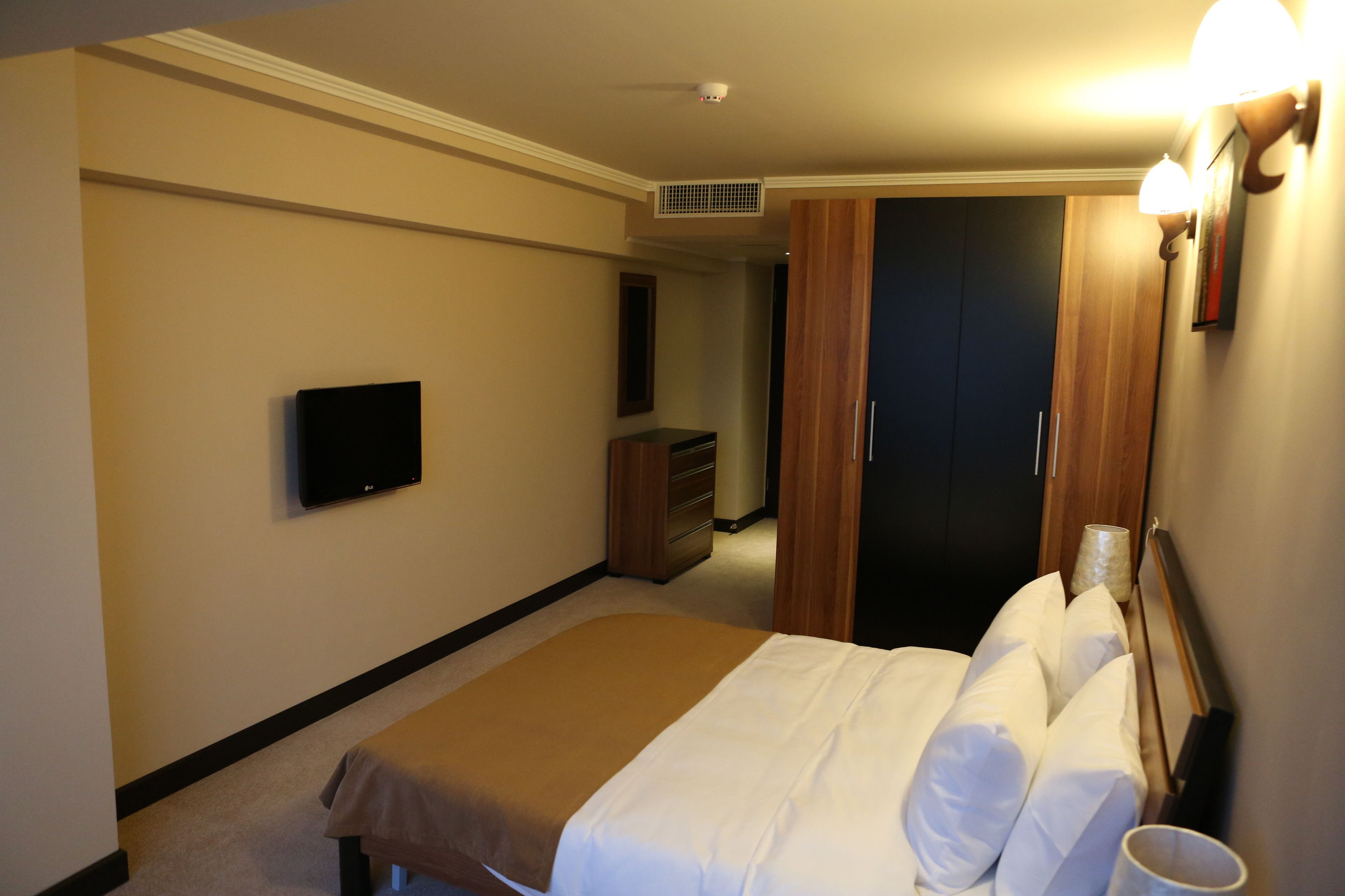 A hotel room with a bed, a TV, a dresser, and a closet.