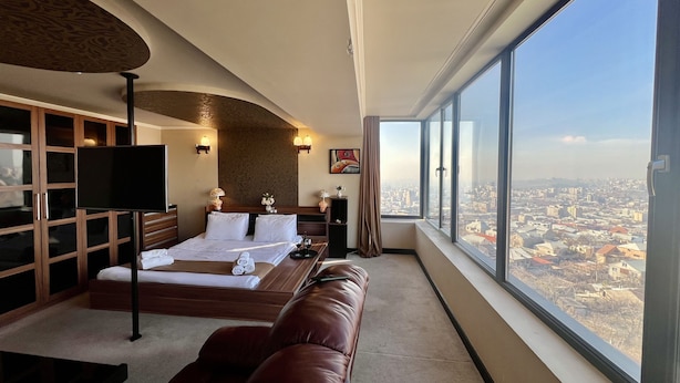 Una camera d'albergo con un letto grande, una TV, un divano e vista sulla città.