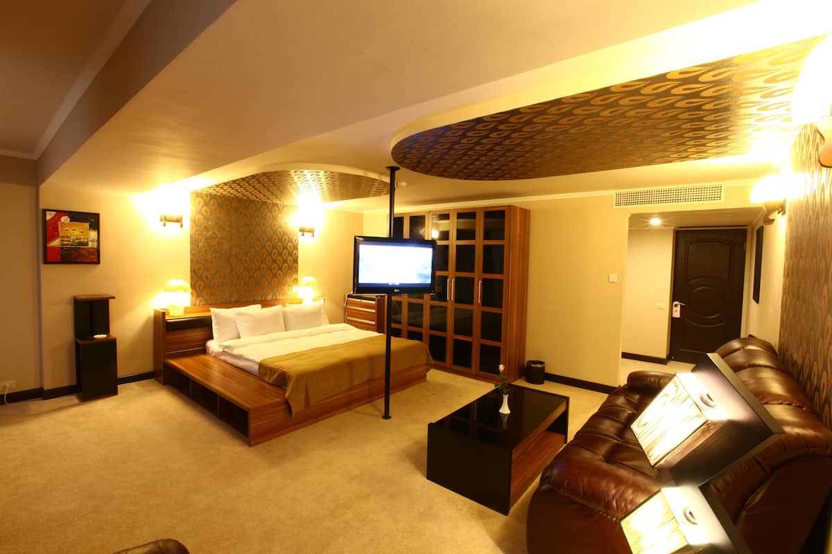 Une chambre d’hôtel avec un lit, une télévision, un canapé et une table basse.