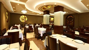 Un ristorante con diversi tavoli e sedie, un lampadario e una finestra con vetrate colorate.