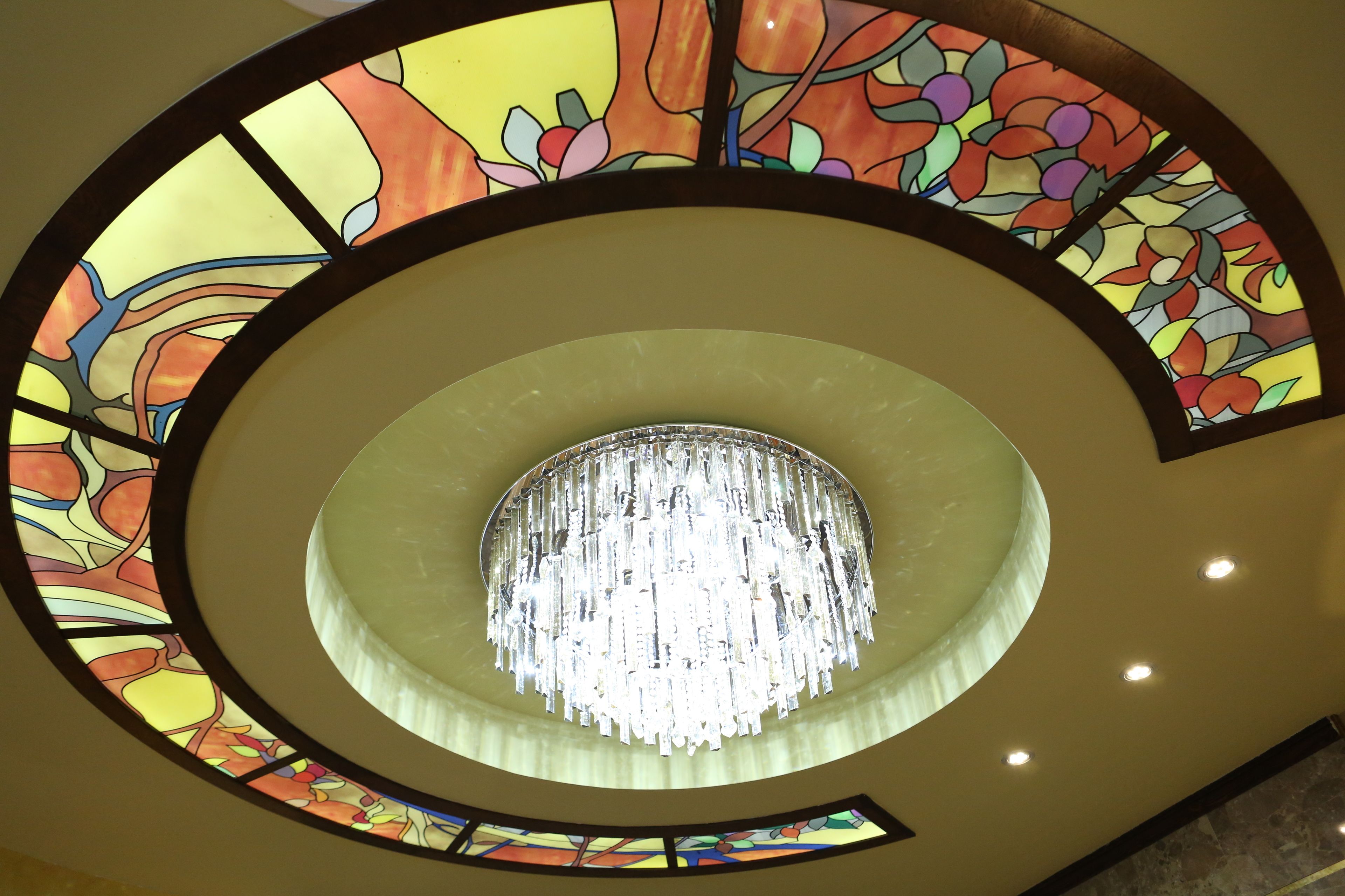 A circular stained glass ceiling with a chandelier.