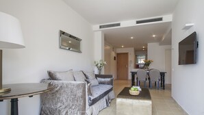A modern living room with a sofa, a coffee table, and a dining area in the background. - Splendom Suites Pau Claris (Barcelona)