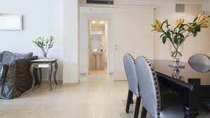 A modern living room with a dining area, a sofa, a coffee table, and a vase with flowers. - Splendom Suites Pau Claris (Barcelona)