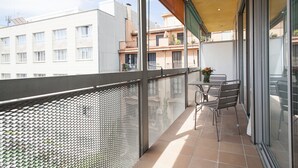 A balcony with a metal railing, a table with chairs, and a view of neighboring buildings. - Splendom Suites Pau Claris (Barcelona)